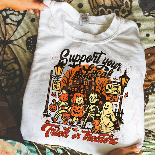 White t-shirt with Halloween-themed design held by a person on a patterned surface