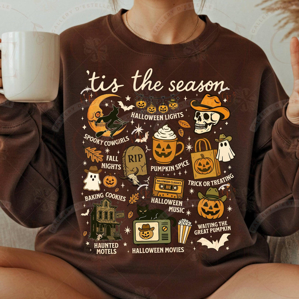 Brown sweatshirt with Halloween-themed graphics and text, worn by a person holding a mug.
