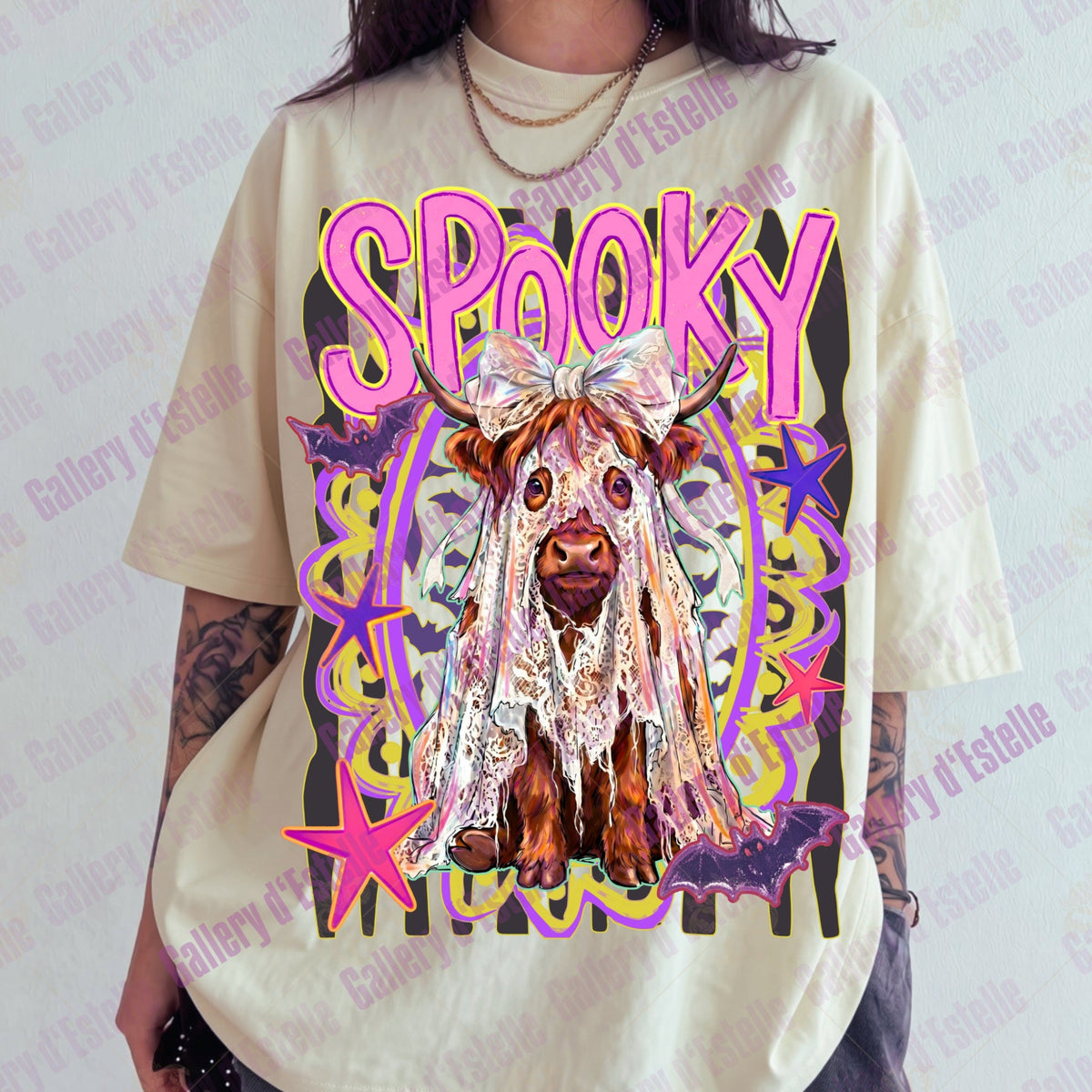 A person wearing an oversized cream-colored graphic t-shirt featuring a colorful 'Spooky' cow illustration with pink lettering and purple, yellow, and white details.