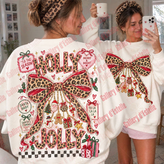 A woman wearing a white Christmas sweatshirt with a large leopard-print bow and 'Holly Jolly' text on the back, shown alongside a mirror selfie of the front view. The sweatshirt features festive graphics including ornaments, gifts, and tags.