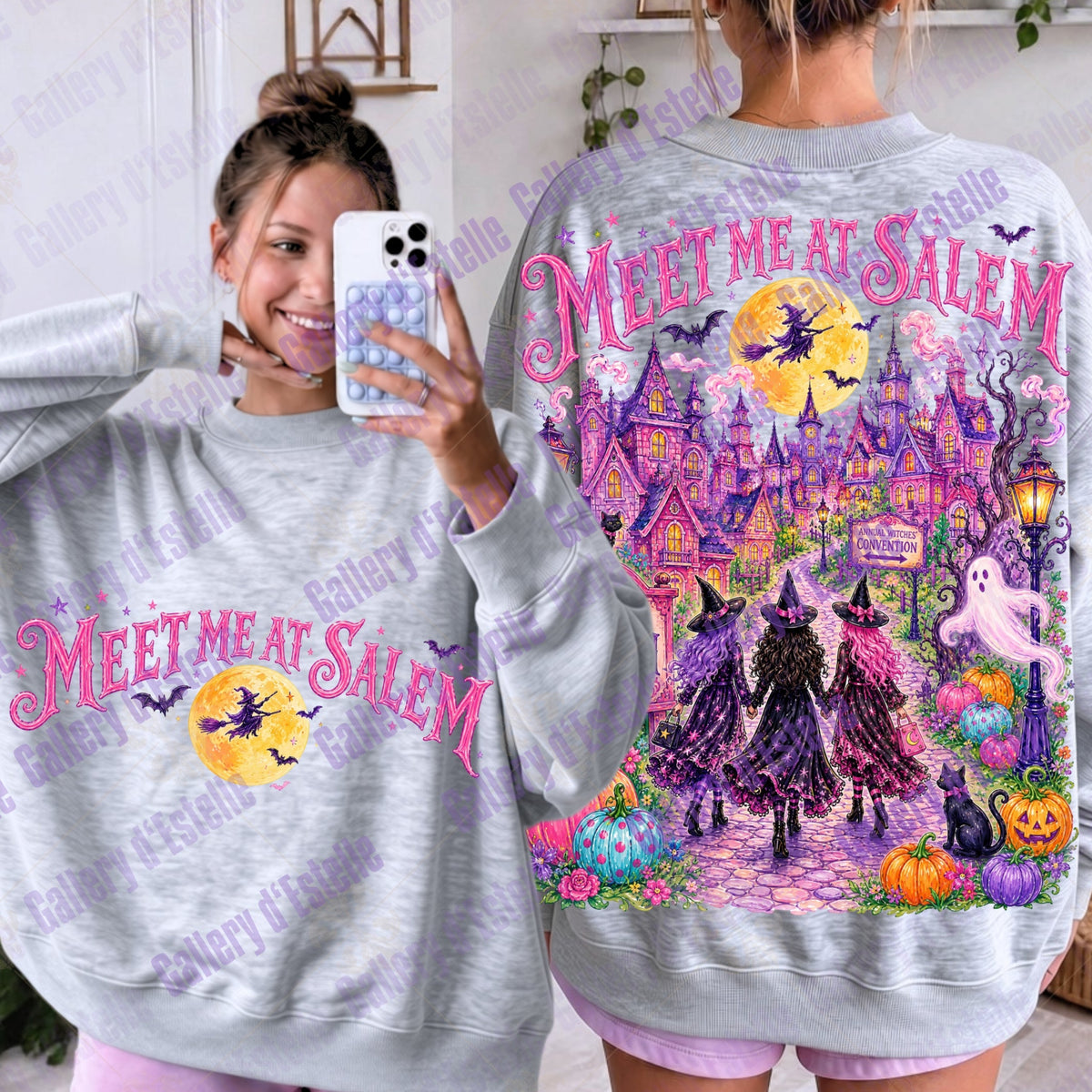 A woman modeling a light gray sweatshirt from both the front and back. The front shows pink 'MEET ME AT SALEM' text over a yellow moon graphic, while the back features a large colorful Halloween scene with witches, a haunted house, pumpkins, ghosts, and the same pink text.