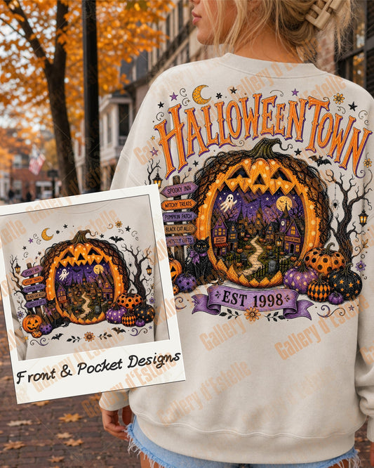 A woman outdoors wearing a white sweatshirt with a large Halloween-themed graphic on the back reading 'HALLOWEENTOWN' and showing a jack-o'-lantern porch scene. A smaller inset shows the matching pocket design.