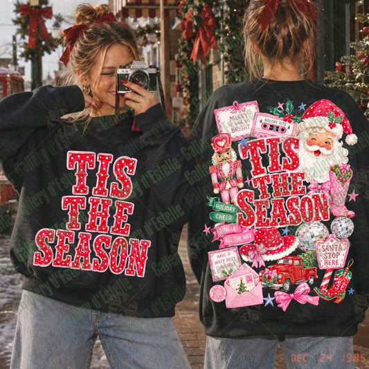 Two women modeling black Christmas sweatshirts outdoors. The left view shows the front with red glittery text reading 'TIS THE SEASON', and the right view shows the back with a large festive collage including Santa, candy canes, cassette tapes, stars, and red lettering.
