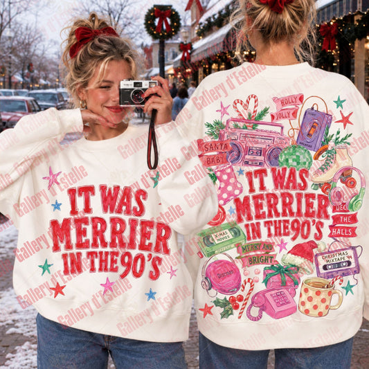 Two women modeling a white Christmas-themed sweatshirt, showing both the front and back designs. The front features the text 'IT WAS MERRIER IN THE 90's' in red, while the back has a colorful retro graphic with a boombox, cassette tape, mug, and candy canes.