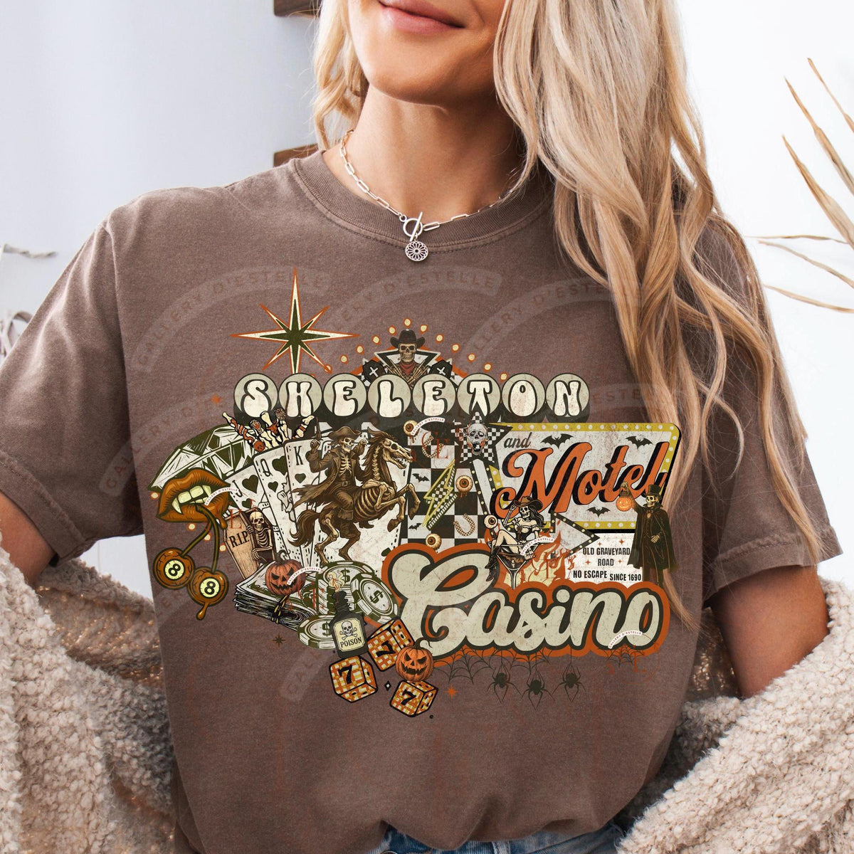 Person wearing a brown t-shirt with 'Skeleton Motel Casino' graphic design.