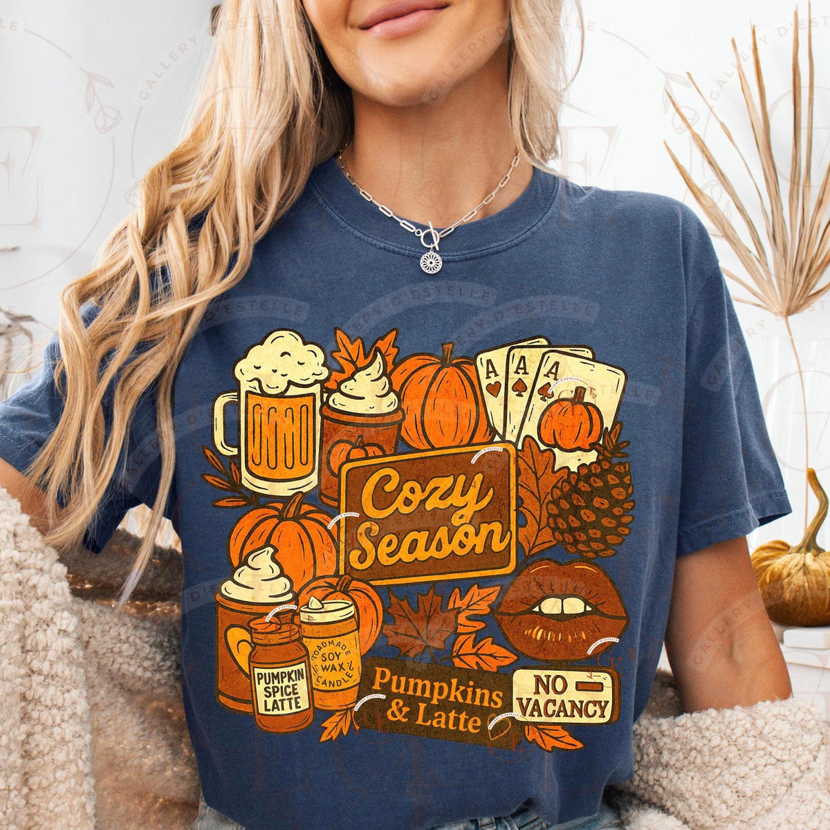 Person wearing a blue t-shirt with 'Cozy Season' graphic design featuring pumpkins and latte.
