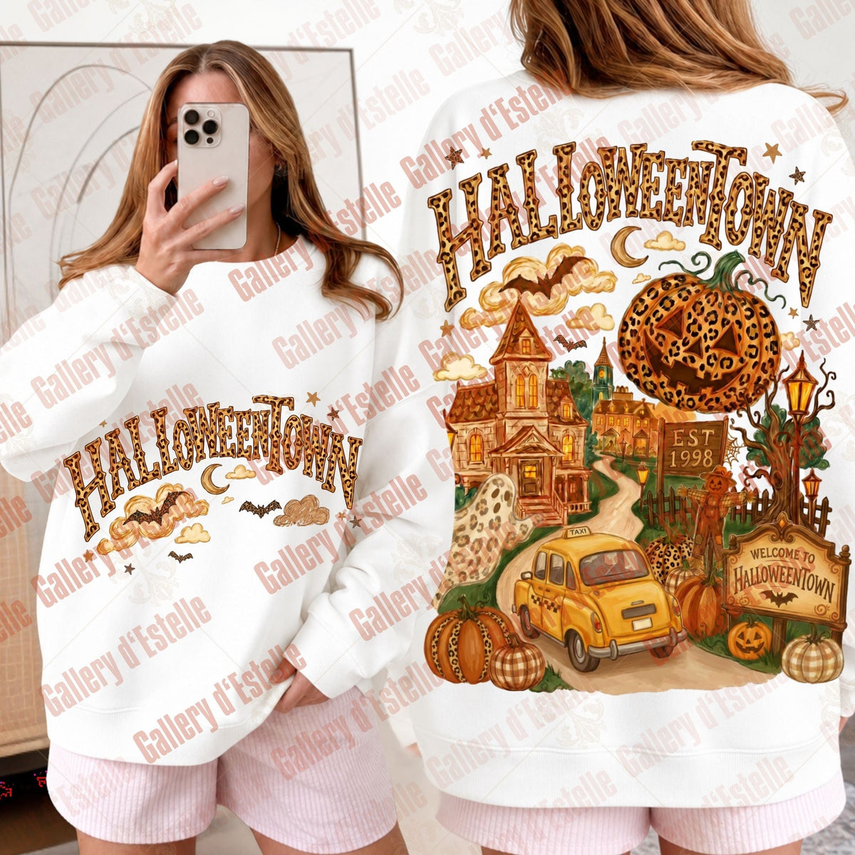 A white crewneck sweatshirt with a large Halloween-themed graphic print. The front view shows 'HALLOWEENTOWN' in leopard letters with clouds and bats, while the back view features a detailed illustration of a haunted house, a yellow vintage car, pumpkins, a spider on a globe, and a 'Welcome to Halloween Town' sign.
