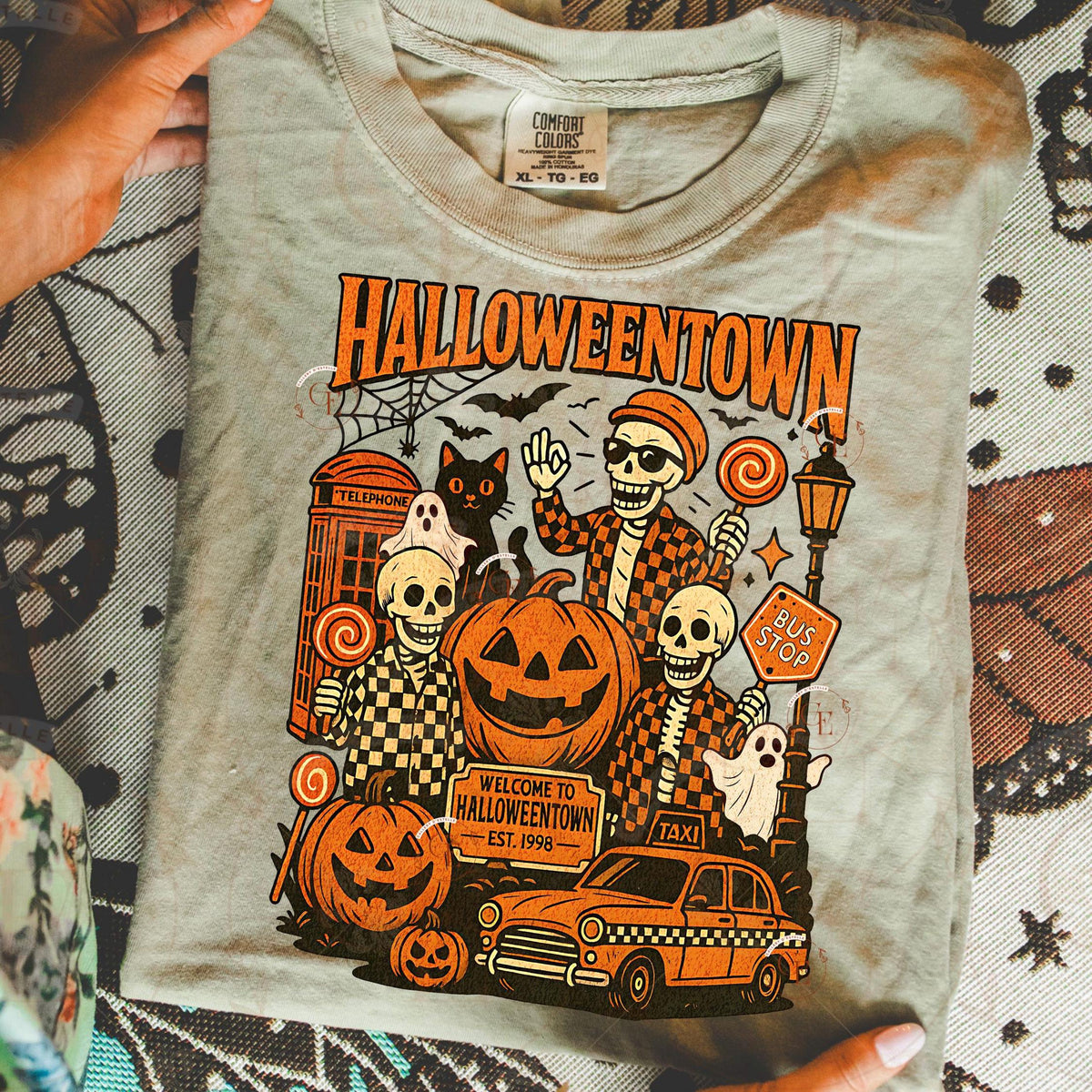 T-shirt with 'Halloweentown' graphic design featuring skeletons, pumpkins, and a taxi.