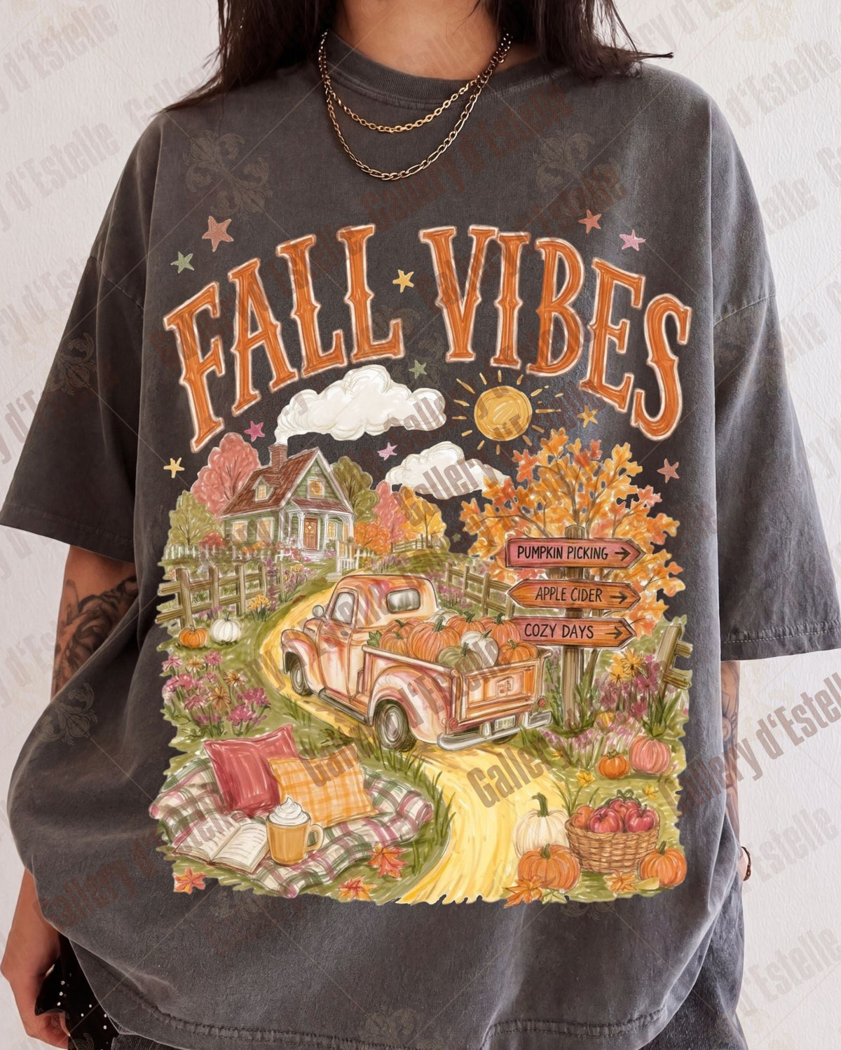 A person wearing an oversized faded charcoal gray graphic T-shirt with a colorful autumn-themed print reading 'FALL VIBES' above an illustrated pickup truck, house, pumpkins, and fall scenery.