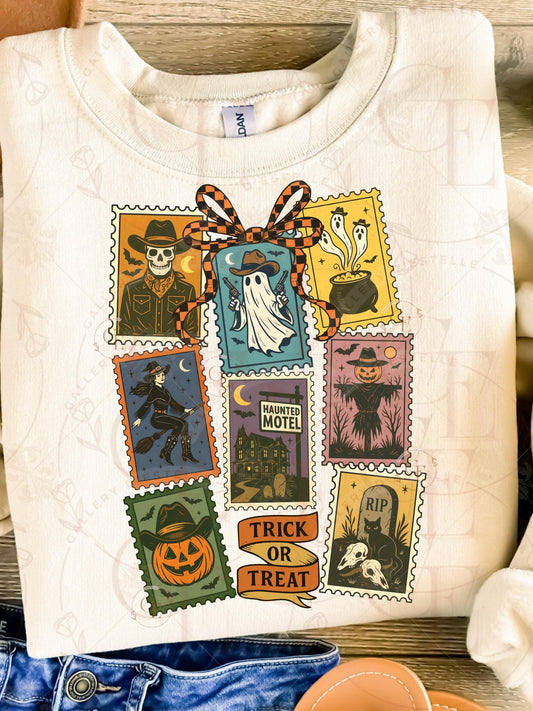White sweatshirt with Halloween-themed postage stamp design on a wooden surface.
