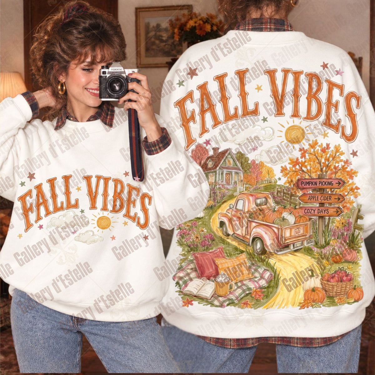 Two models wearing a white sweatshirt with 'FALL VIBES' printed on the front and back. The back features a large, colorful autumn-themed graphic with a pickup truck, fall leaves, a house, and pumpkins.