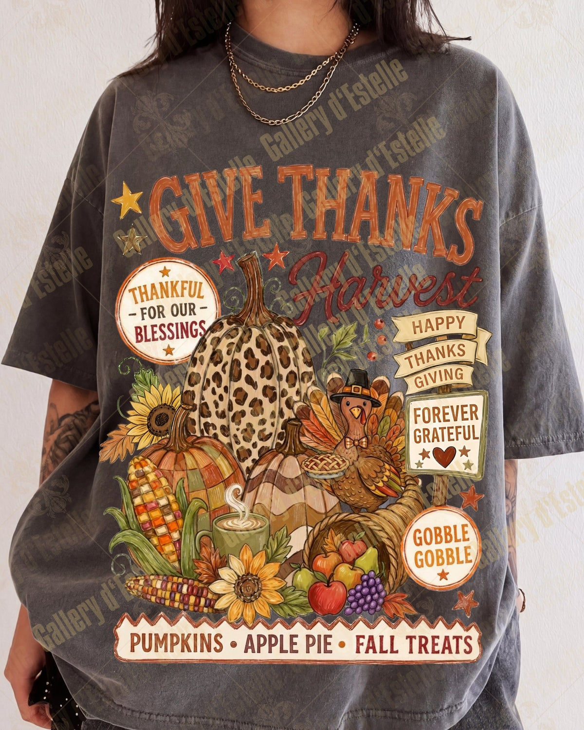 A person wearing an oversized dark gray graphic T-shirt with a large autumn Thanksgiving print featuring pumpkins, sunflowers, apples, and text including 'GIVE THANKS' and 'THANKFUL FOR OUR BLESSINGS'.