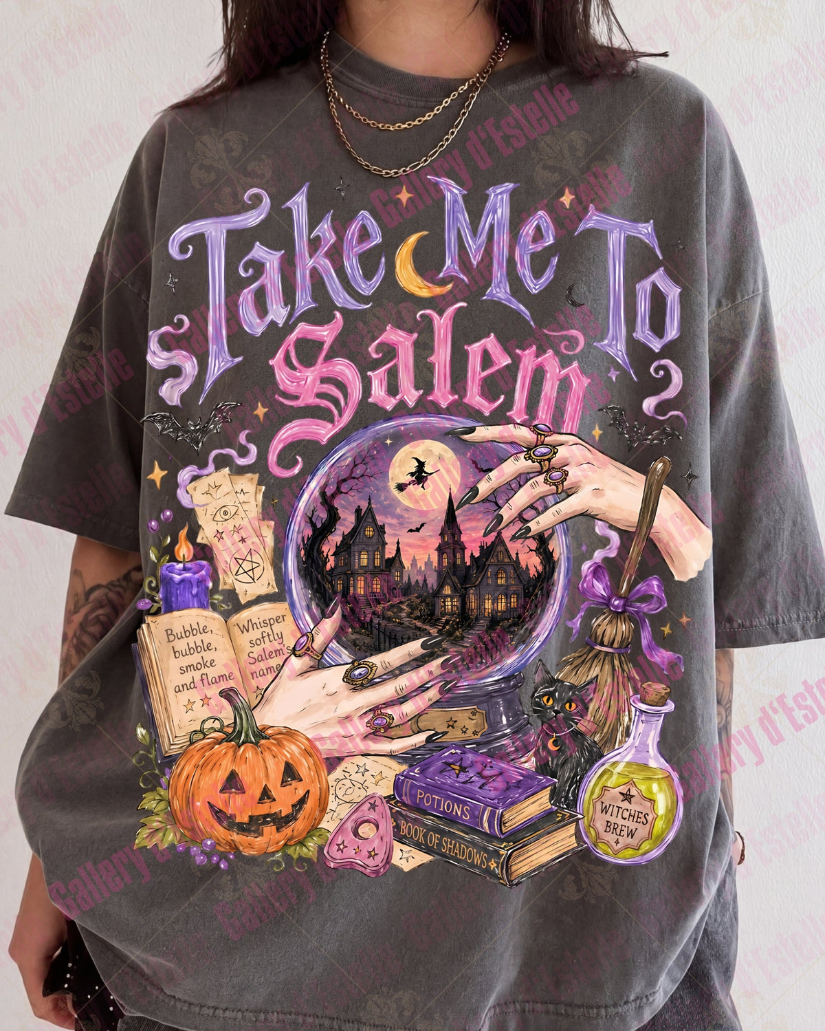 A person wearing an oversized charcoal gray graphic t-shirt with a colorful Halloween-themed print reading 'Take Me To Salem'. The graphic features a crystal ball, witch's hat, potion bottle, and jack-o'-lantern.