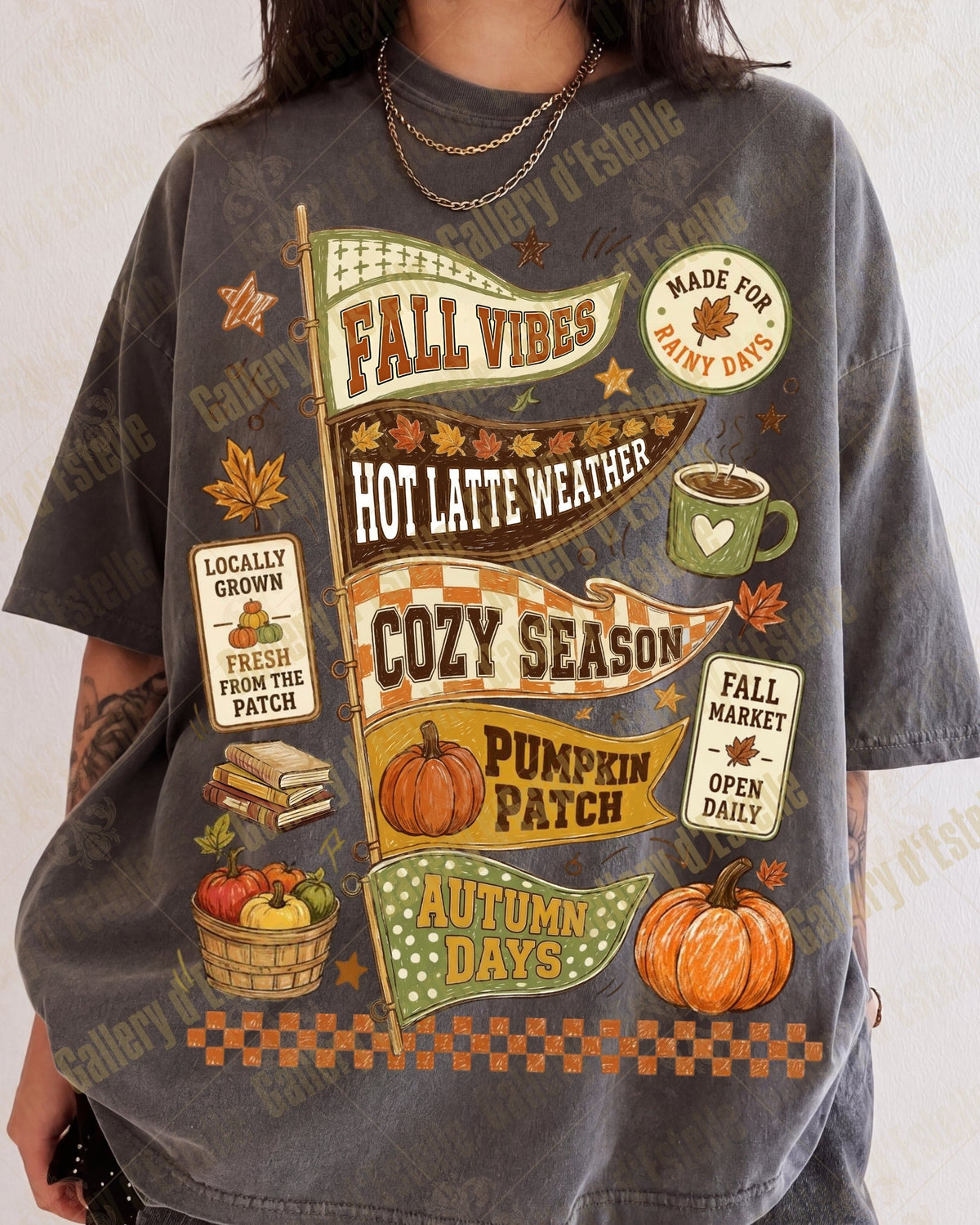 A person wearing an oversized charcoal gray graphic T-shirt with autumn-themed printed designs including pumpkins, fall leaves, a coffee cup, and text such as 'Fall Vibes,' 'Cozy Season,' and 'Pumpkin Patch.'.