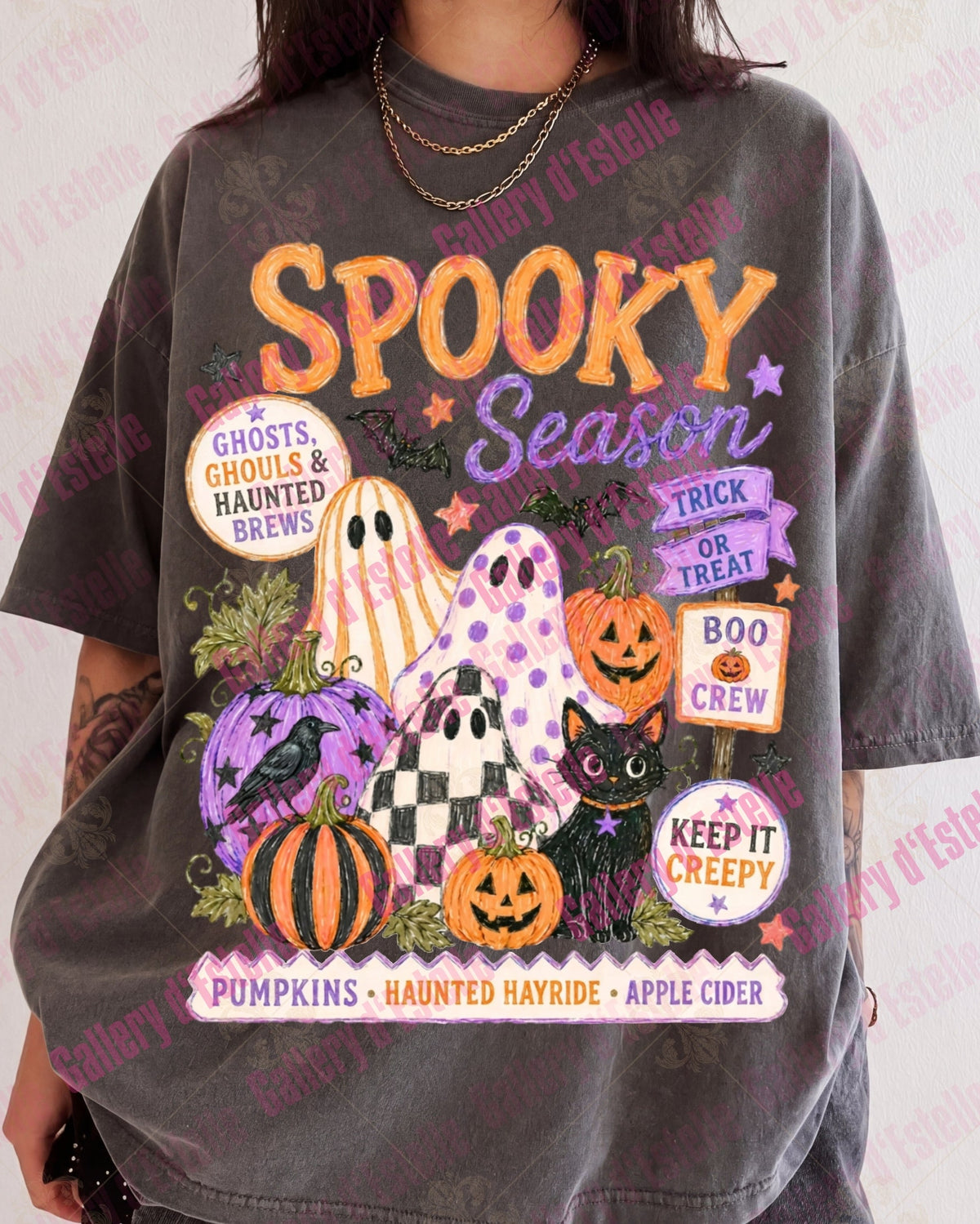 A person wearing an oversized charcoal gray graphic T-shirt with a colorful Halloween-themed print reading 'Spooky Season' and featuring pumpkins, ghosts, and signs.