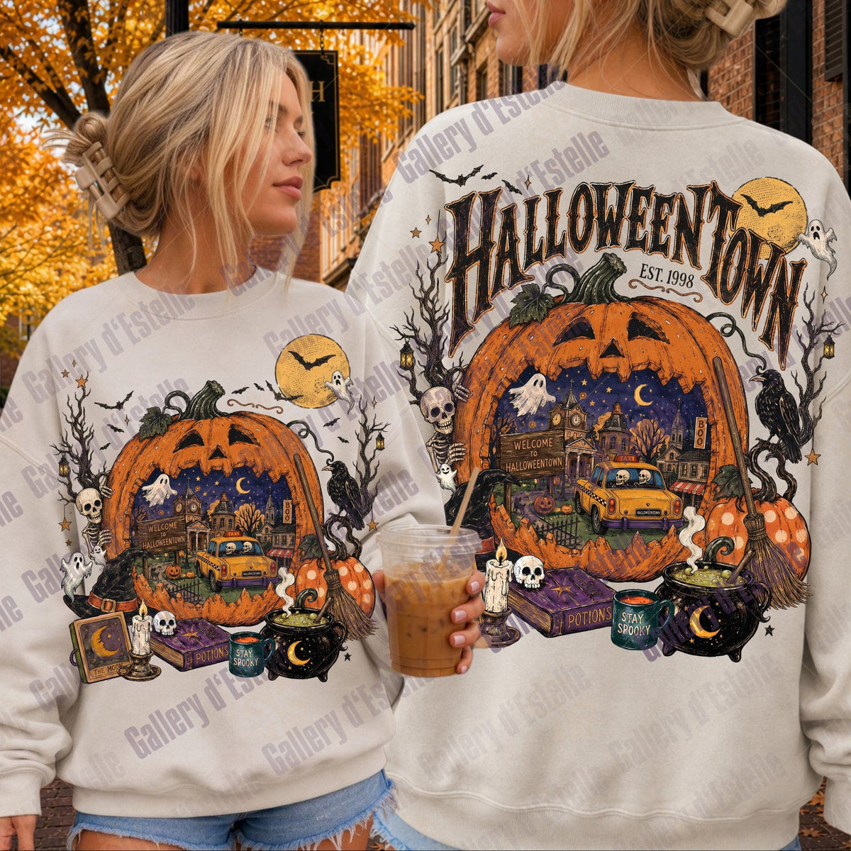 Two women modeling matching off-white sweatshirts with a large Halloween-themed graphic print. The front view shows a jack-o'-lantern, cauldron, potion bottles, and a clock, while the back view shows 'Halloween Town Est. 1998"