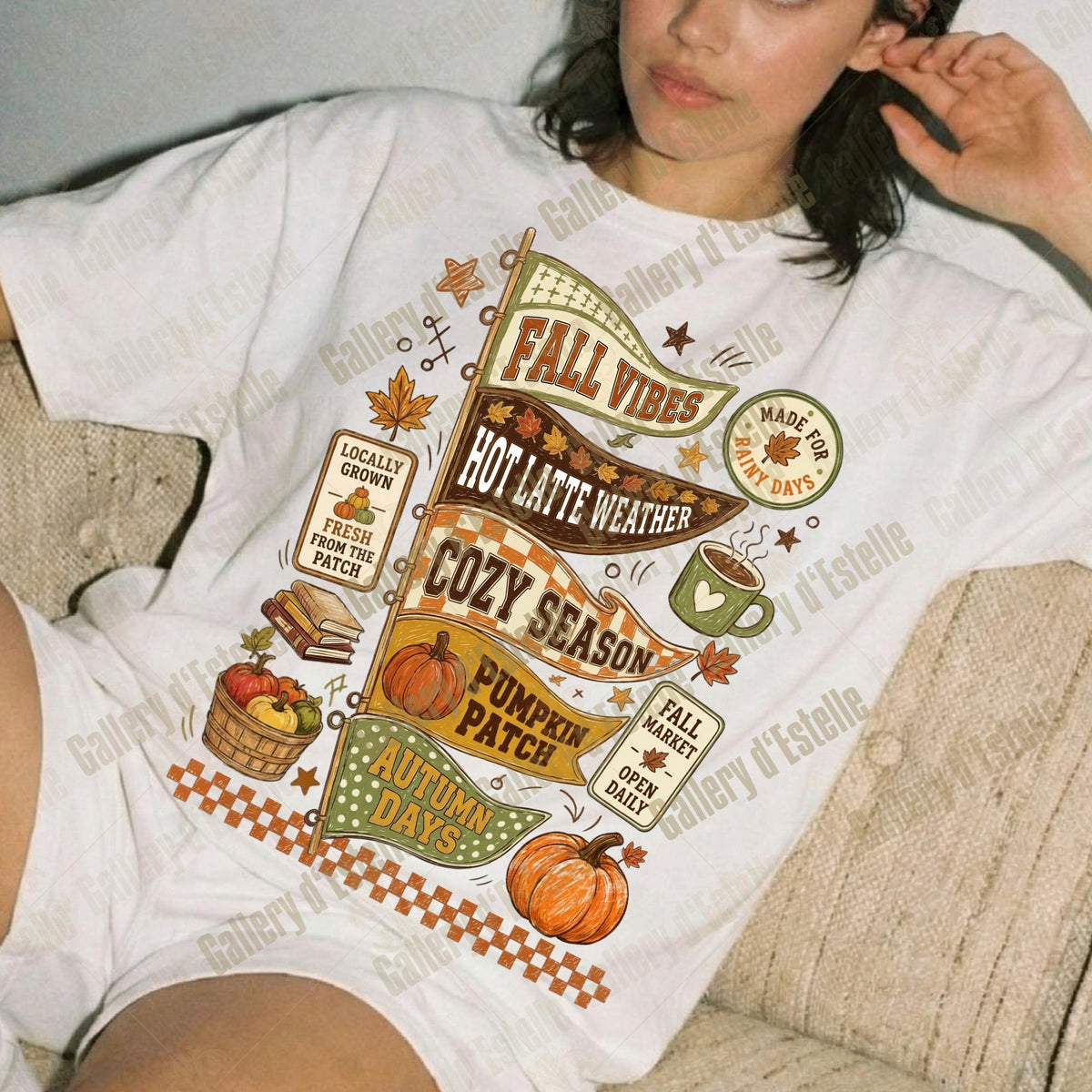 A woman reclining on a beige couch wearing a white graphic T-shirt with autumn-themed text and illustrations including pumpkins, leaves, a mug, and seasonal phrases.