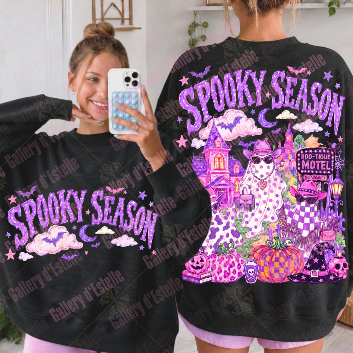 A woman shown in a mirror selfie wearing a black sweatshirt with a purple 'Spooky Season' graphic on the front, alongside a larger back view of the sweatshirt featuring a colorful haunted house, ghost, pumpkins, and motel design.