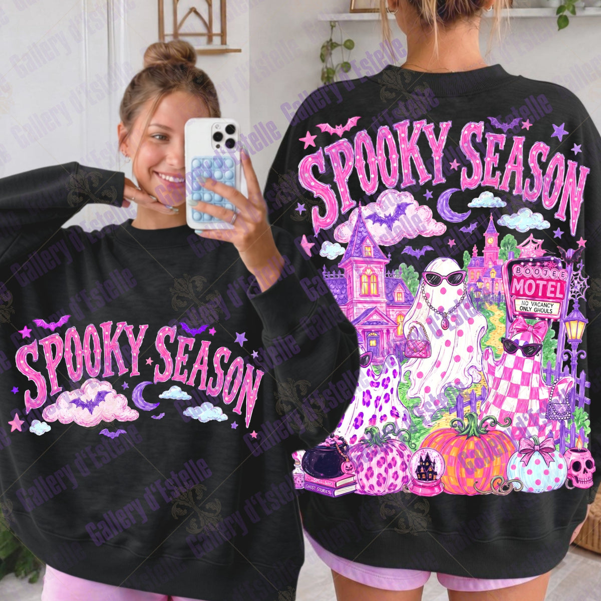 A woman modeling a black sweatshirt in a mirror selfie showing both the front and back designs. The sweatshirt features 'SPOOKY SEASON' in pink text with purple, pink, and orange Halloween-themed graphics on the back, including a haunted castle, spooky motel, glam ghouls and pumpkins.