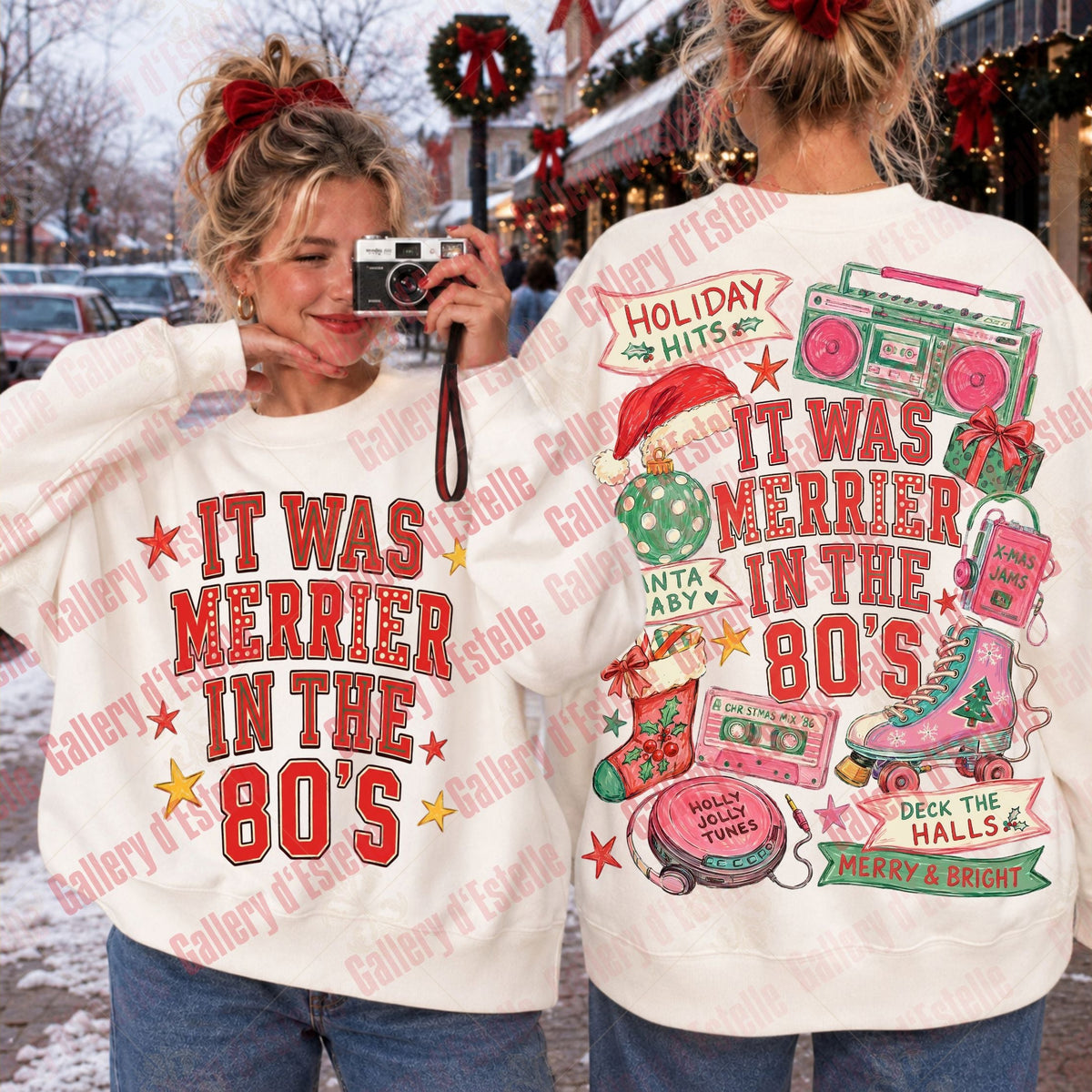 Two women modeling a white sweatshirt with a colorful retro 1980s holiday graphic. One shows the front with the text 'IT WAS MERRIER IN THE 80'S' in red, and the other shows the back with additional holiday-themed illustrations including boomboxes, a pink stocking, and a Christmas tree.