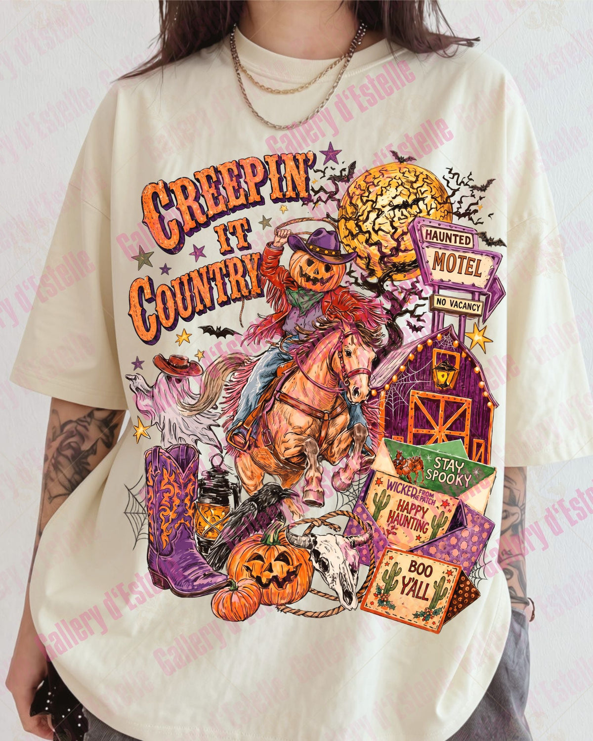A person wearing an oversized cream-colored graphic t-shirt with a colorful Halloween-themed design featuring a horse, a spooky cowboy, pumpkins, and a motel sign. The t-shirt has 'Creepin' It Country' written on the front.
