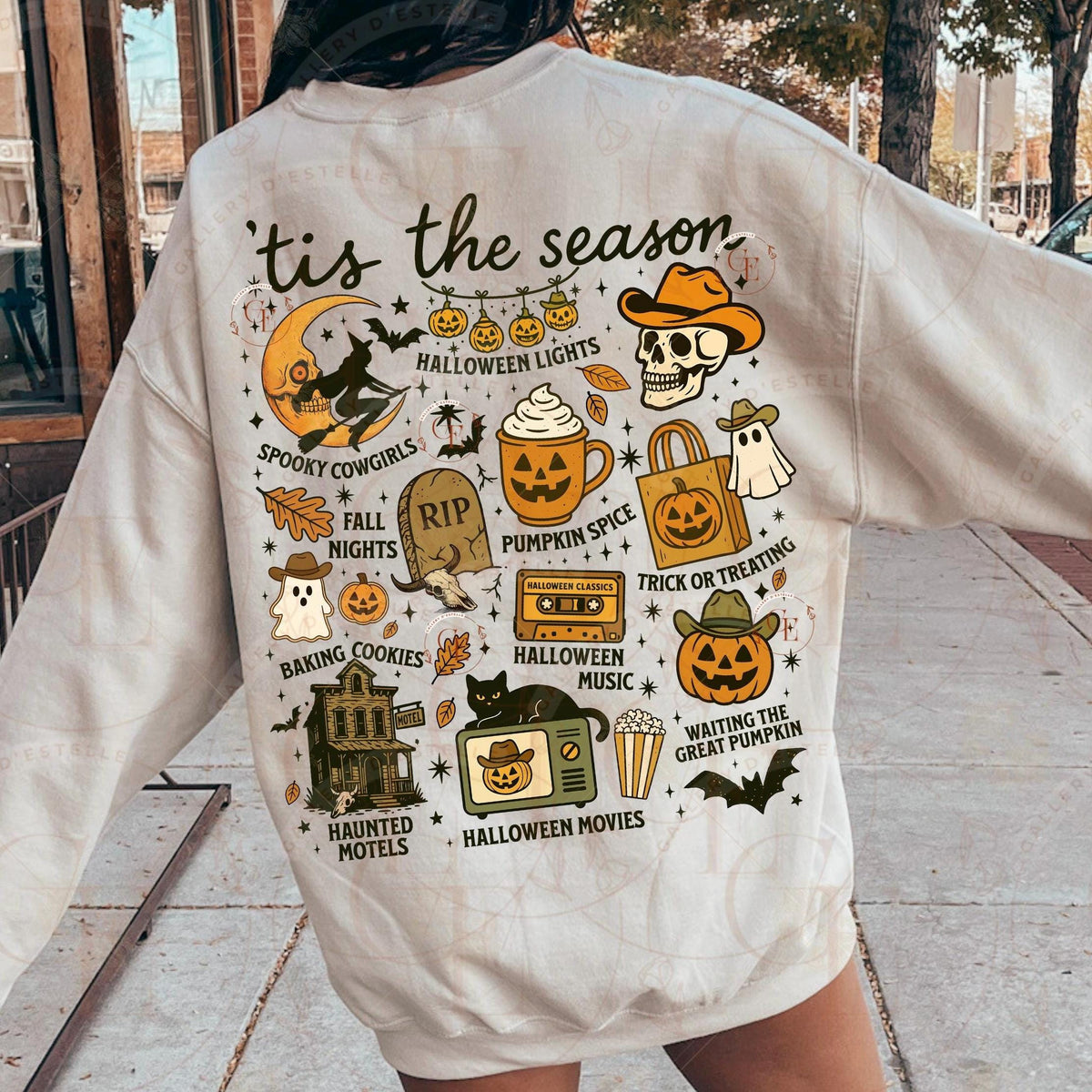 Beige sweatshirt with Halloween-themed graphics and text on a person outdoors.