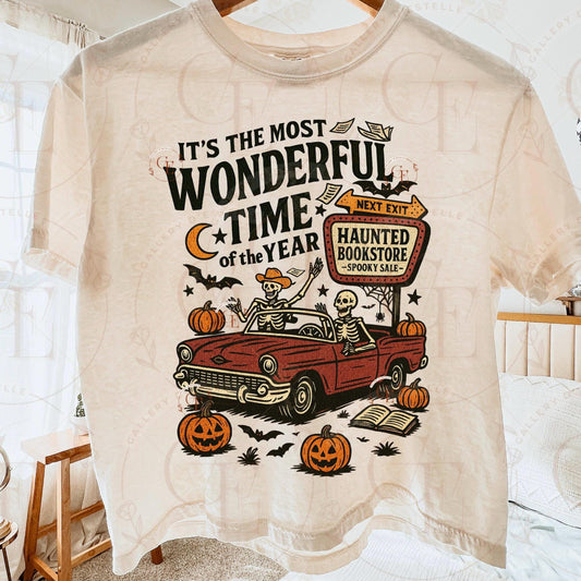 Beige t-shirt with Halloween-themed design featuring a red car, pumpkins, and skeletons.