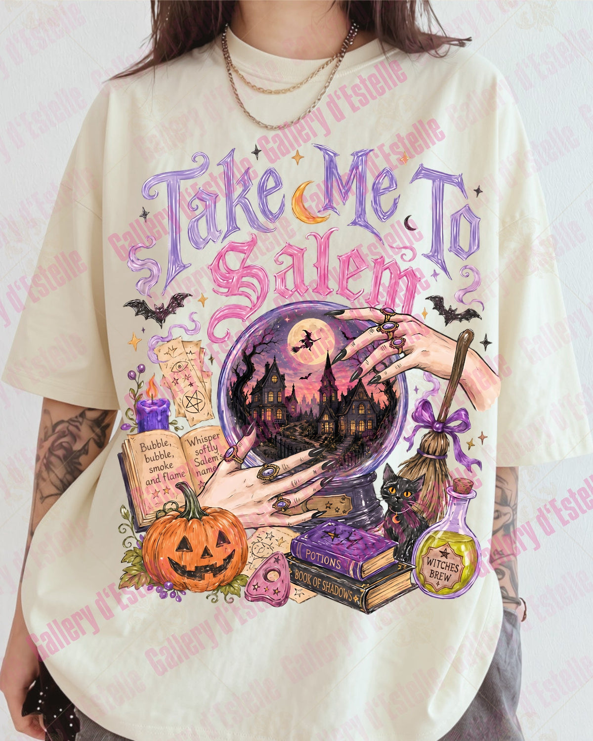 A person wearing an oversized cream-colored graphic t-shirt with a colorful Halloween-themed print that reads 'Take Me To Salem'. The graphic features a witch's cauldron, a jack-o'-lantern, potion bottles, and bats.
