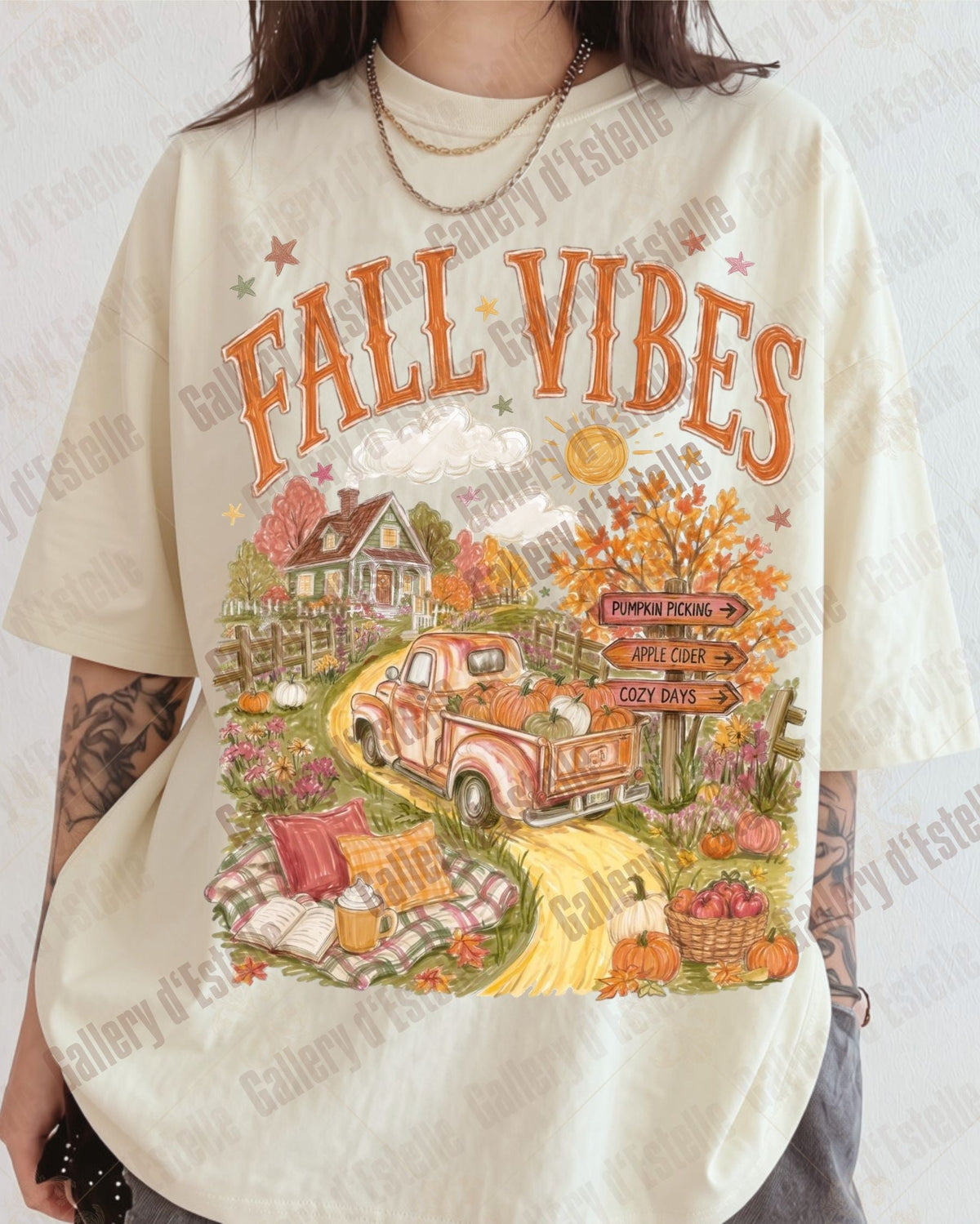 A person wearing an oversized cream-colored graphic t-shirt with a colorful autumn 'FALL VIBES' design featuring a vintage pickup truck, pumpkins, and a cabin.