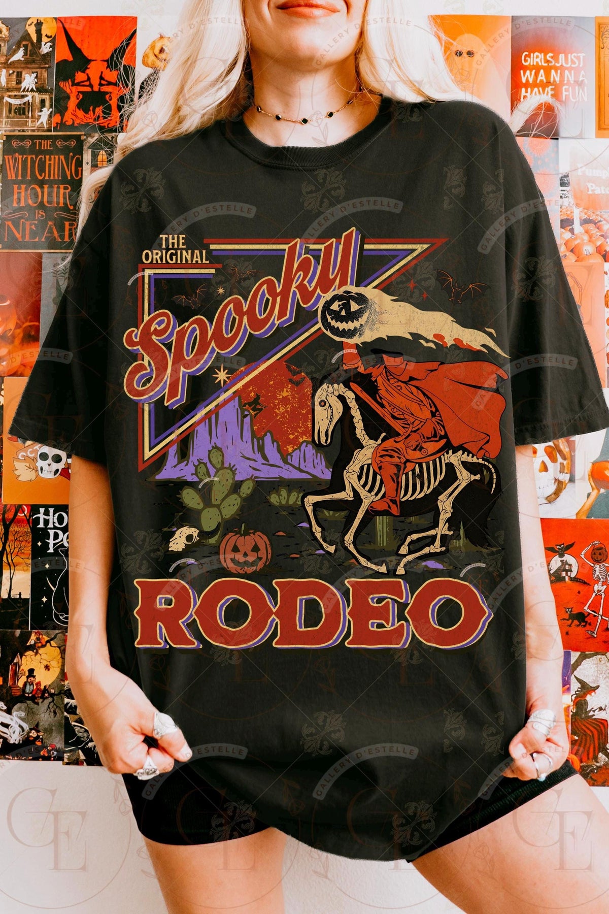 Person wearing a black t-shirt with 'Spooky Rodeo' graphic design in front of Halloween-themed decorations.