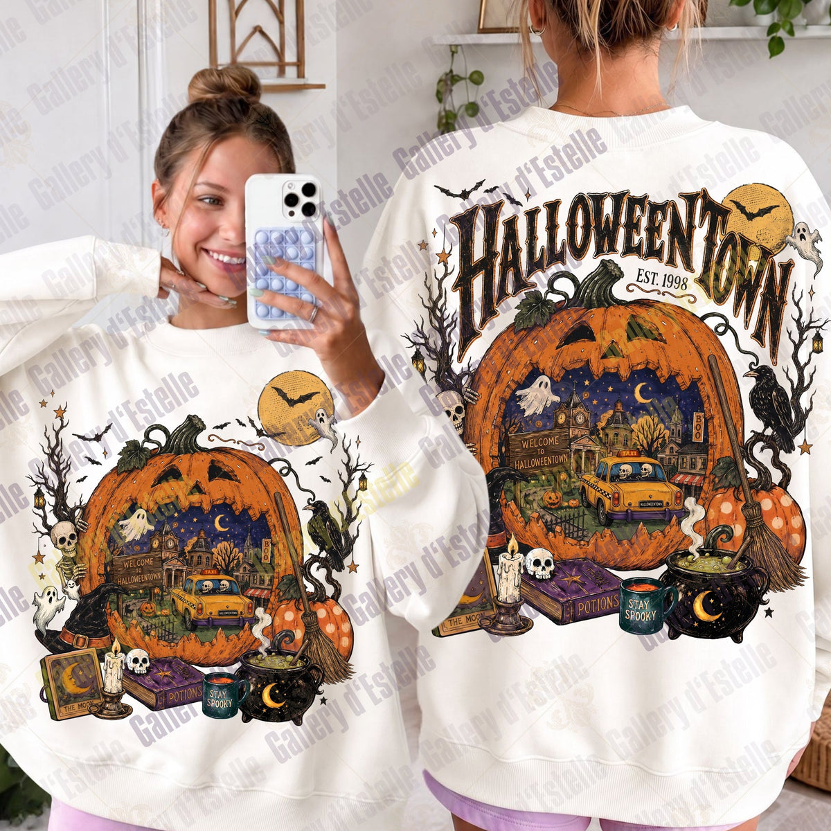 A person modeling a white sweatshirt shown from both front and back. The sweatshirt features a large Halloween-themed graphic with a jack-o'-lantern, haunted house scene, bats, cauldron, skulls, and the text 'HALLOWEENTOWN EST. 1998'