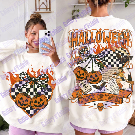 A woman wearing an oversized white - colored graphic sweatshirt with a Halloween design. The graphic features orange jack-o'-lanterns, a black and white checkered flag, playing cards, a witch, and the words 'HALLOWEEN' and 'TRICK OR TREAT'.