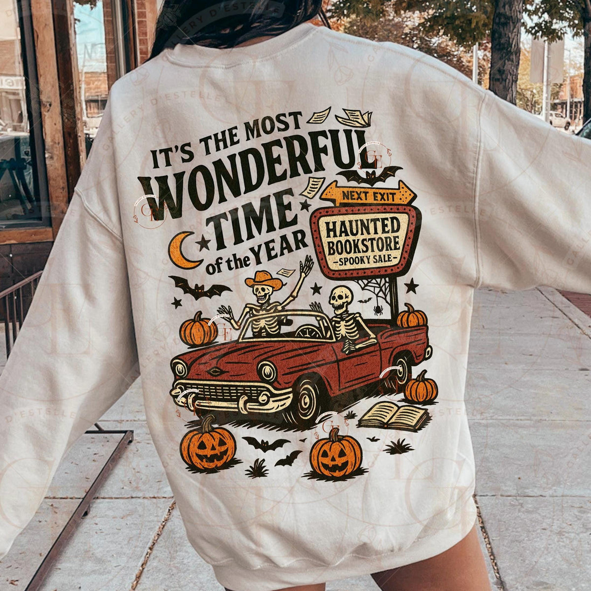 Person wearing a shirt with Halloween-themed design featuring a red car, skeletons, and pumpkins.