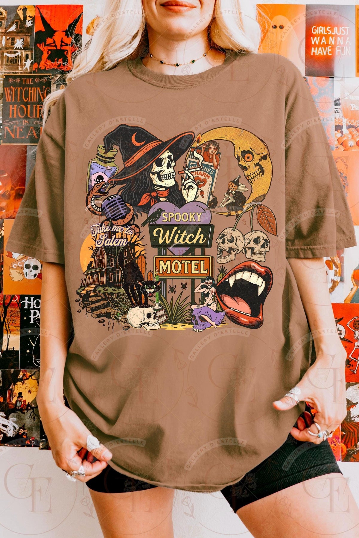 Person wearing a brown t-shirt with Halloween-themed graphics in front of an orange wall with Halloween decorations.